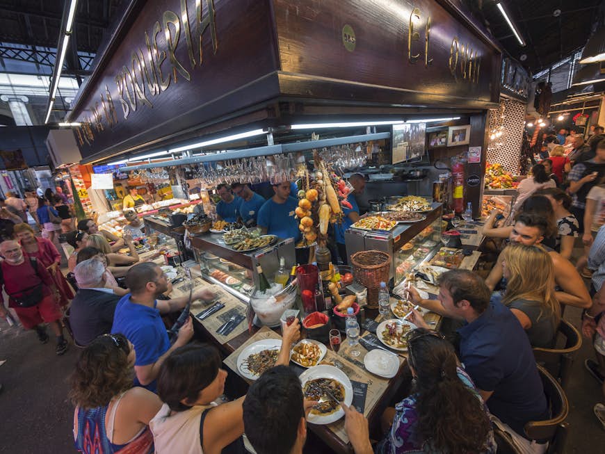 A counter full of people eating tapas at Mercat de la Boqueria, Barcelona