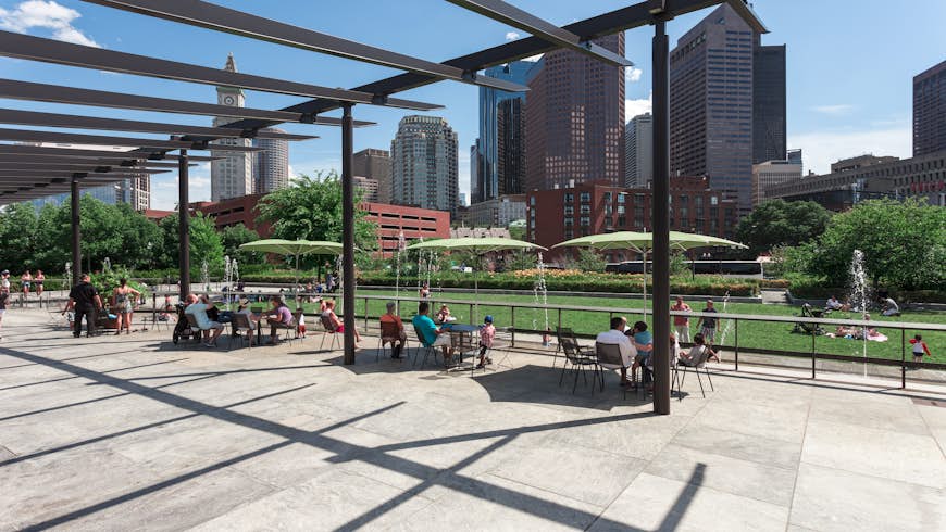 People sitting at tables under umbrellas at the Rose Fitzgerald Kennedy Greenway's North End Park 