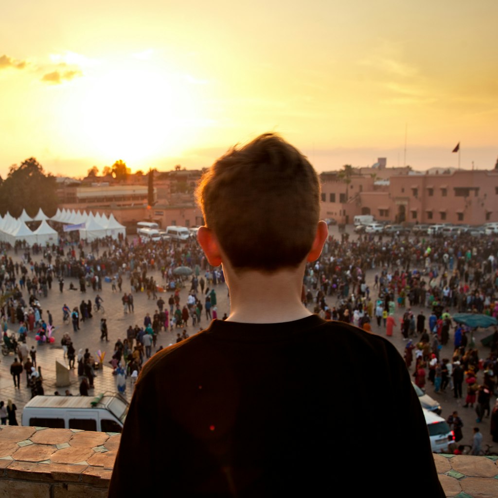 Boy looking out onto Jemaa el Fna square in Marrakech, Morocco at sunset.