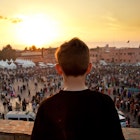 Boy looking out onto Jemaa el Fna square in Marrakech, Morocco at sunset.