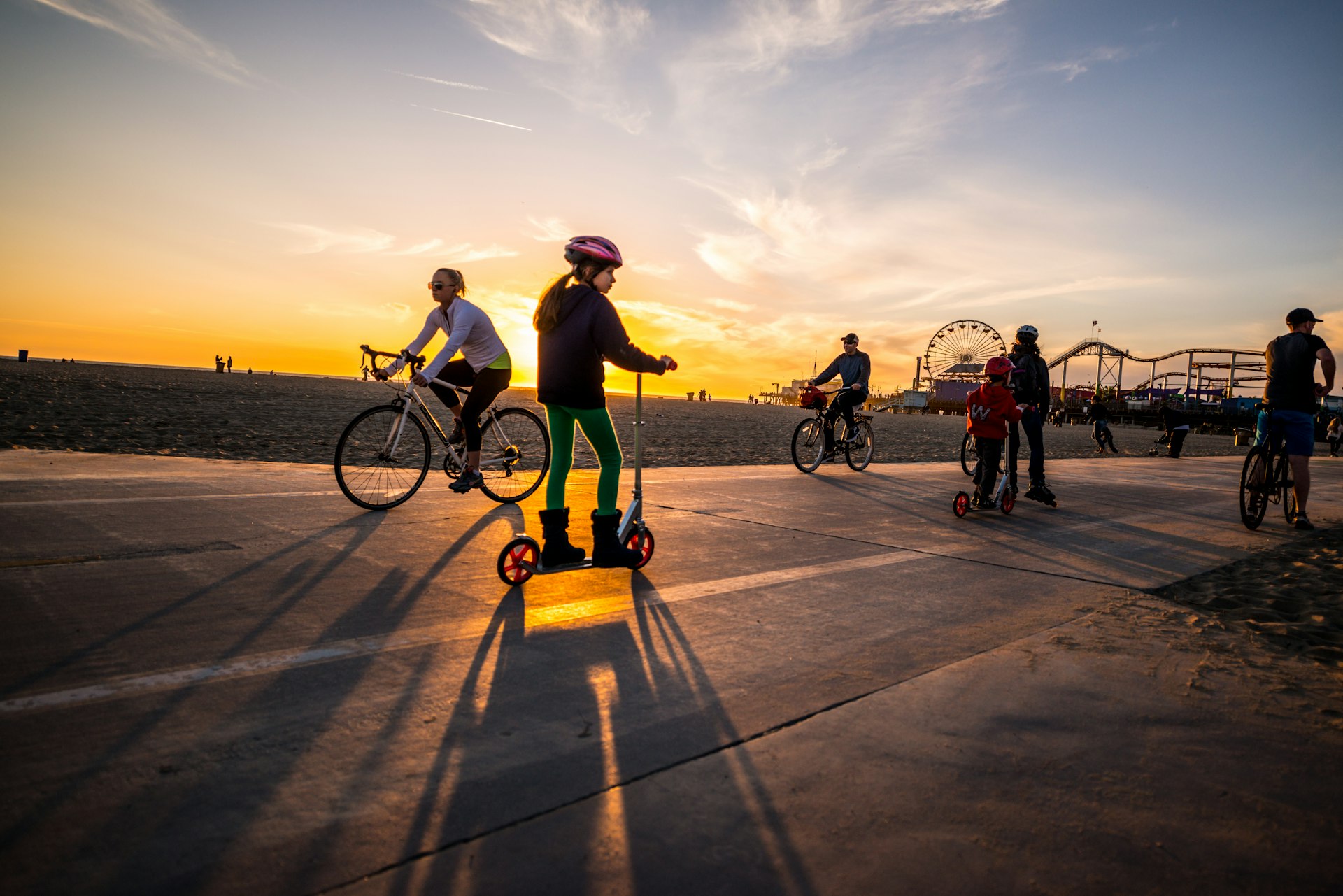 People cycling and jogging on Santa Monica beach during sunset