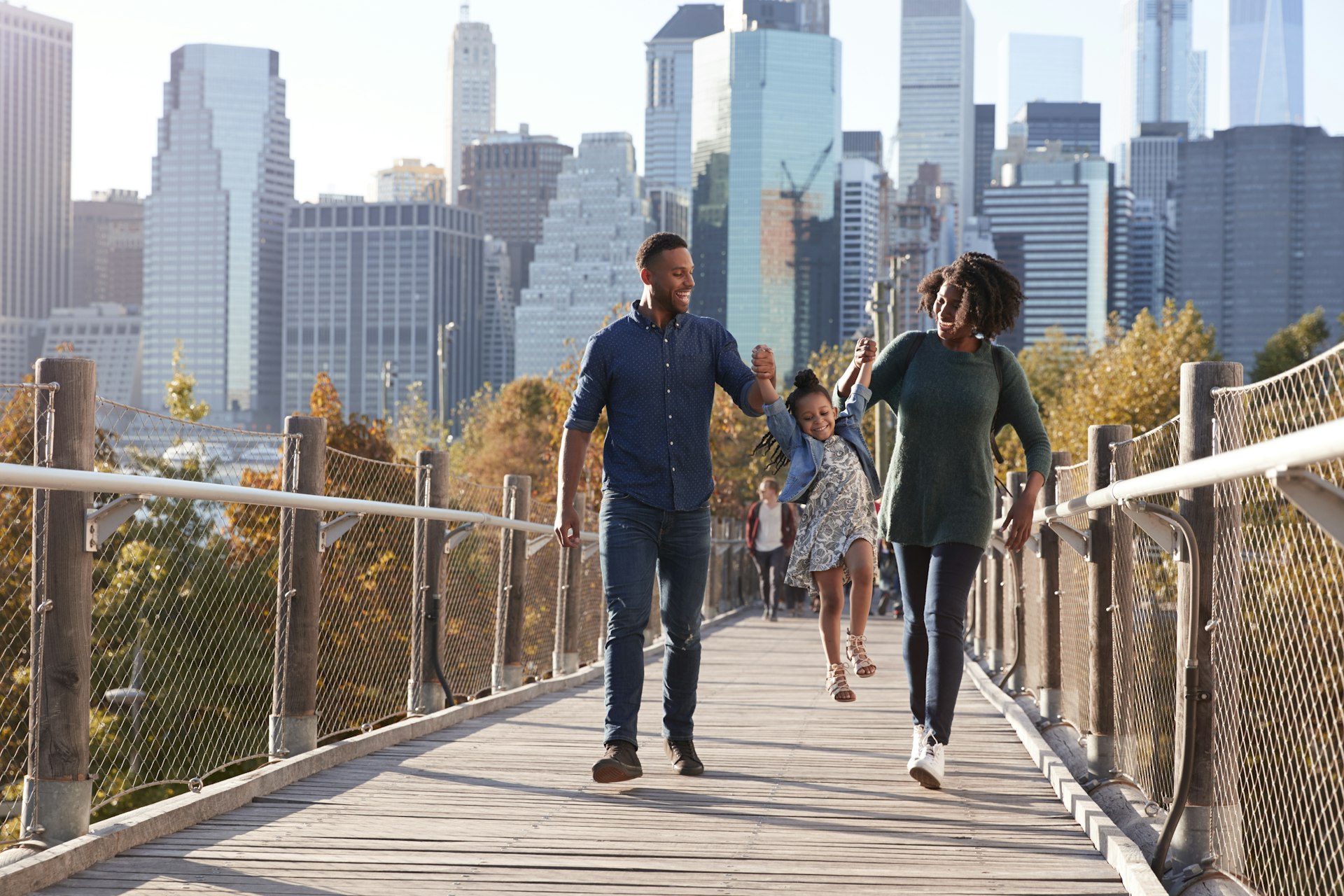 Young family with daughter taking a walk on footbridge in New York