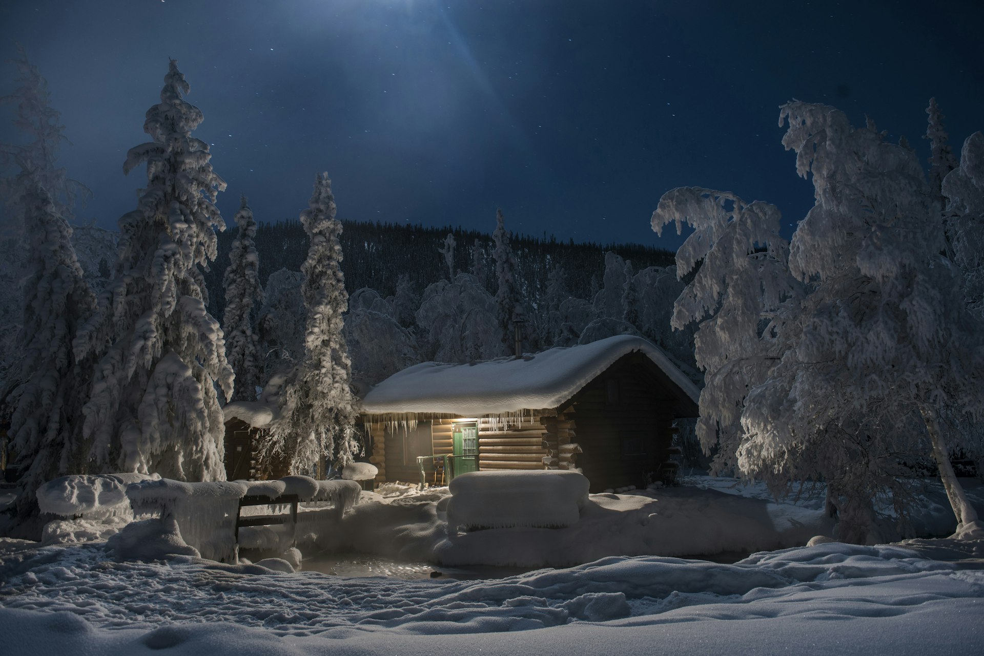 A log cabin surrounded by snow at night