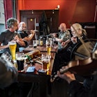 Irish musicians perform while seated on a table at the John Hewitt pub in Belfast.