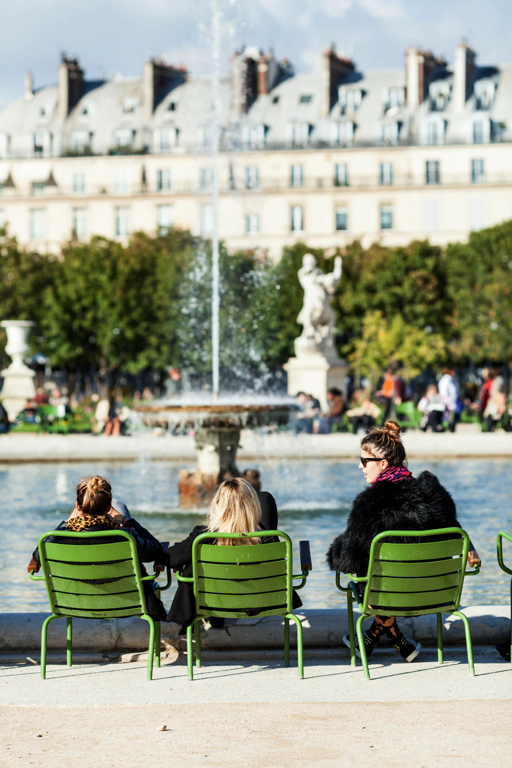Three women sitting beside fountain in Paris. 