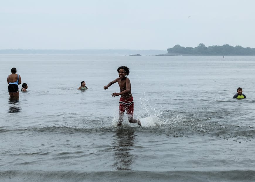 Kids play in the shallow waters of Orchard Beach on a cloudy day in the Bronx, NUC