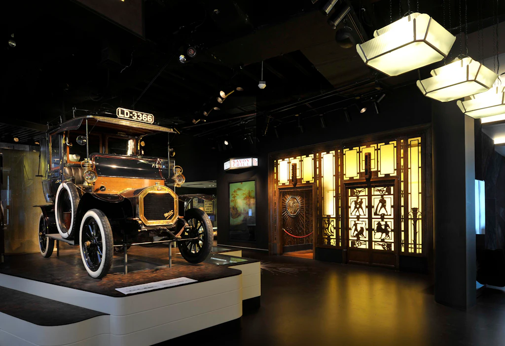An old-fashioned taxi stands on display near a reconstruction of a 1920s art-deco style lift