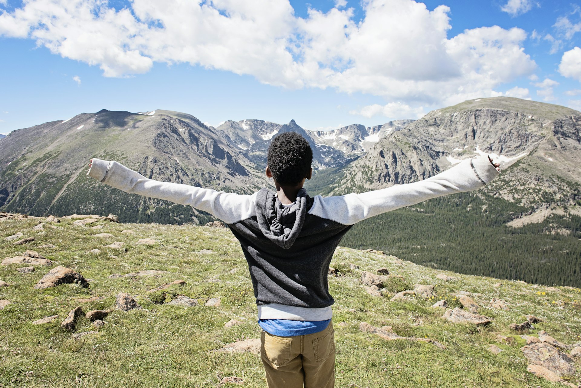 A boy with arms outstretched enjoying views of Rocky Mountain National Park, Colorado