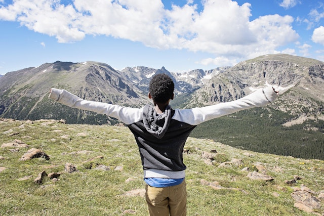 A boy with arms outstretched enjoying views of Rocky Mountain National Park, Colorado