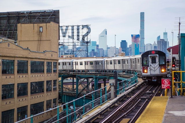 A subway train pulling into an elevated platform in NYC