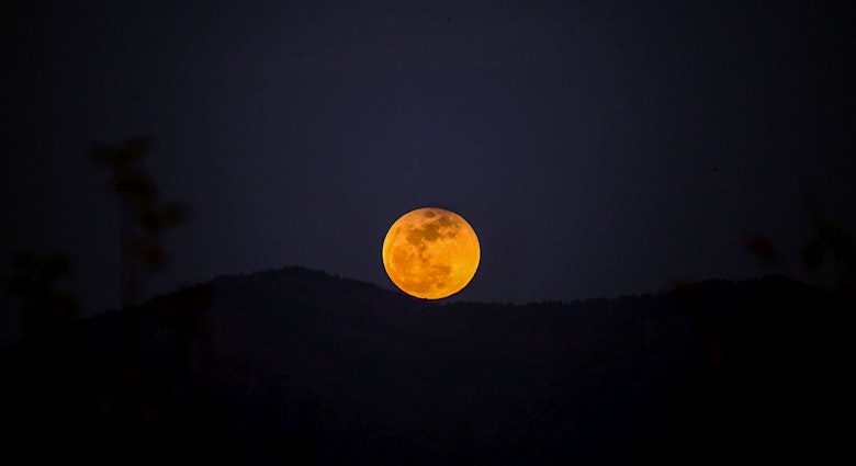 A picture taken on January 31, 2018 shows the moon rising behind a mountain during a lunar eclipse, referred to as the "super blue blood moon" near Syria-Turkey border at the Hassa district in Hatay..Stargazers across large swaths of the globe had the chance to witness a rare "super blue blood Moon" on January 31, 2018, when Earth's shadow bathed our satellite in a coppery hue. The celestial show was the result of the Sun, Earth, and Moon lining up perfectly for a lunar eclipse just as the Moon is near its closest orbit point to Earth, making it appear "super" large.. / AFP PHOTO / OZAN KOSE        (Photo credit should read OZAN KOSE/AFP via Getty Images)