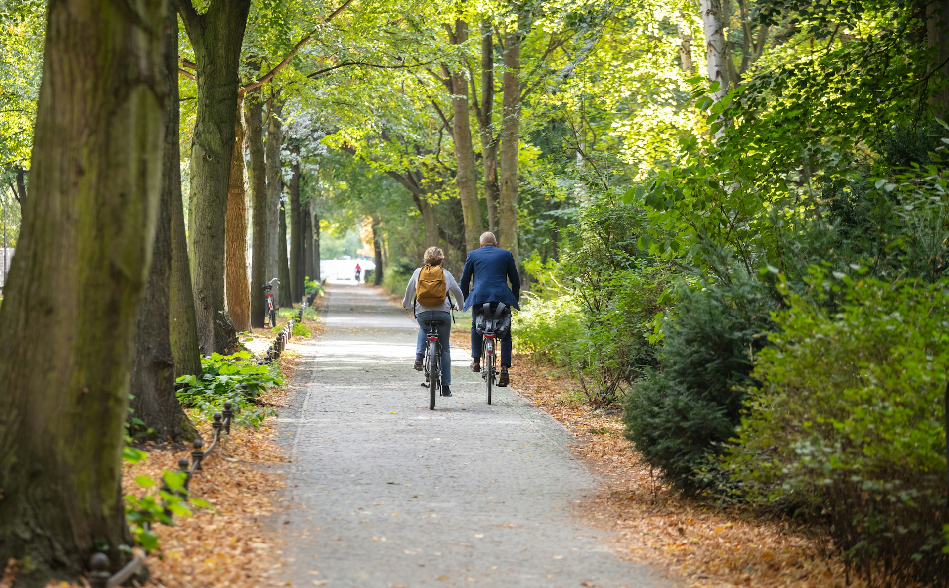 Two people cycle through Tiergarten Park in Berlin