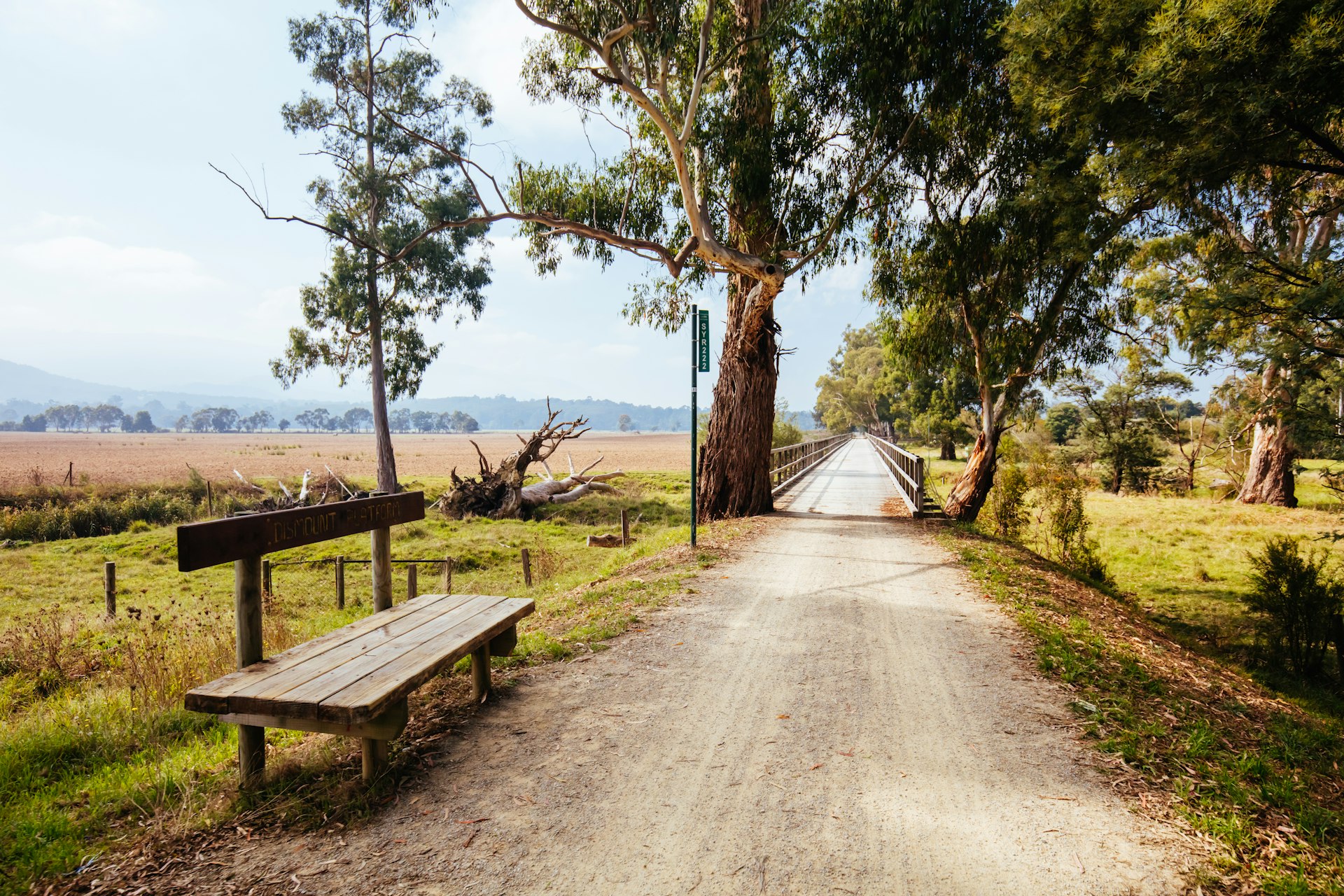 A narrow, straight walking path runs through green fields between Lilydale and Warburton in Australia. 