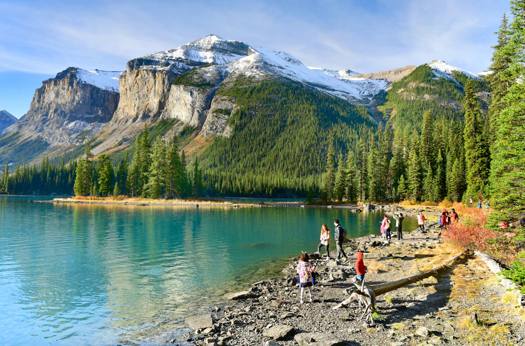 Visitors view a beautiful turquiose lake with mountains in the background. 