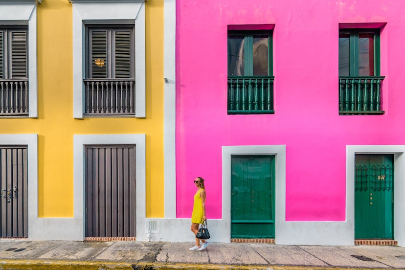 December 12, 2017: Woman in a yellow dress in front of Colourful facades in Old San Juan.