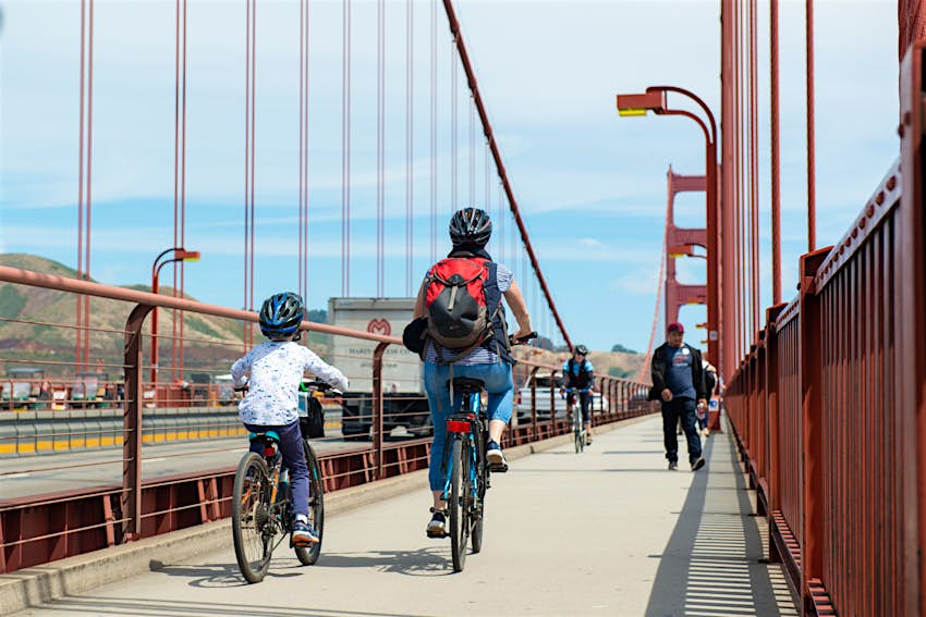 An adult and a child cycle along the Golden Gate Bridge in San Francisco.