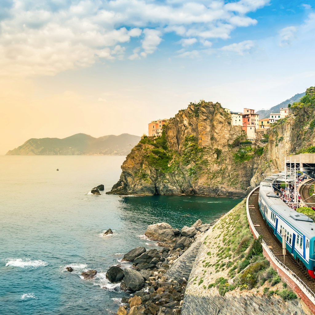 Train station on the coast in the small village of Manarola with colorful houses on cliff overlooking sea.