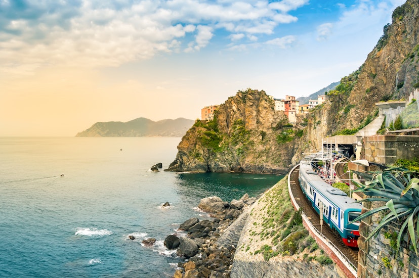 Train station on the coast in the small village of Manarola with colorful houses on cliff overlooking sea.