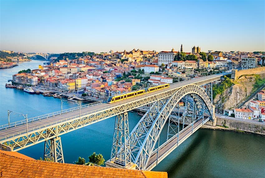 Um comboio do metro atravessa a Ponte Dom Louise com a histórica cidade do Porto por trás.
