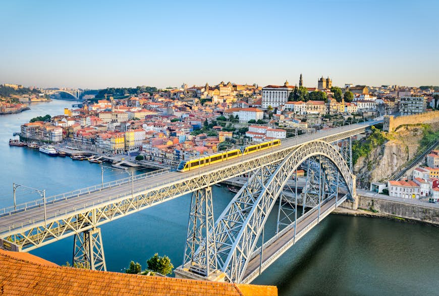A metro train crosses the Dom Luiz bridge with the historic city of Porto beyond.