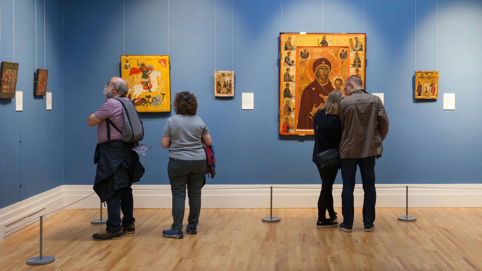 People stand in an art gallery looking at the paintings on the wall