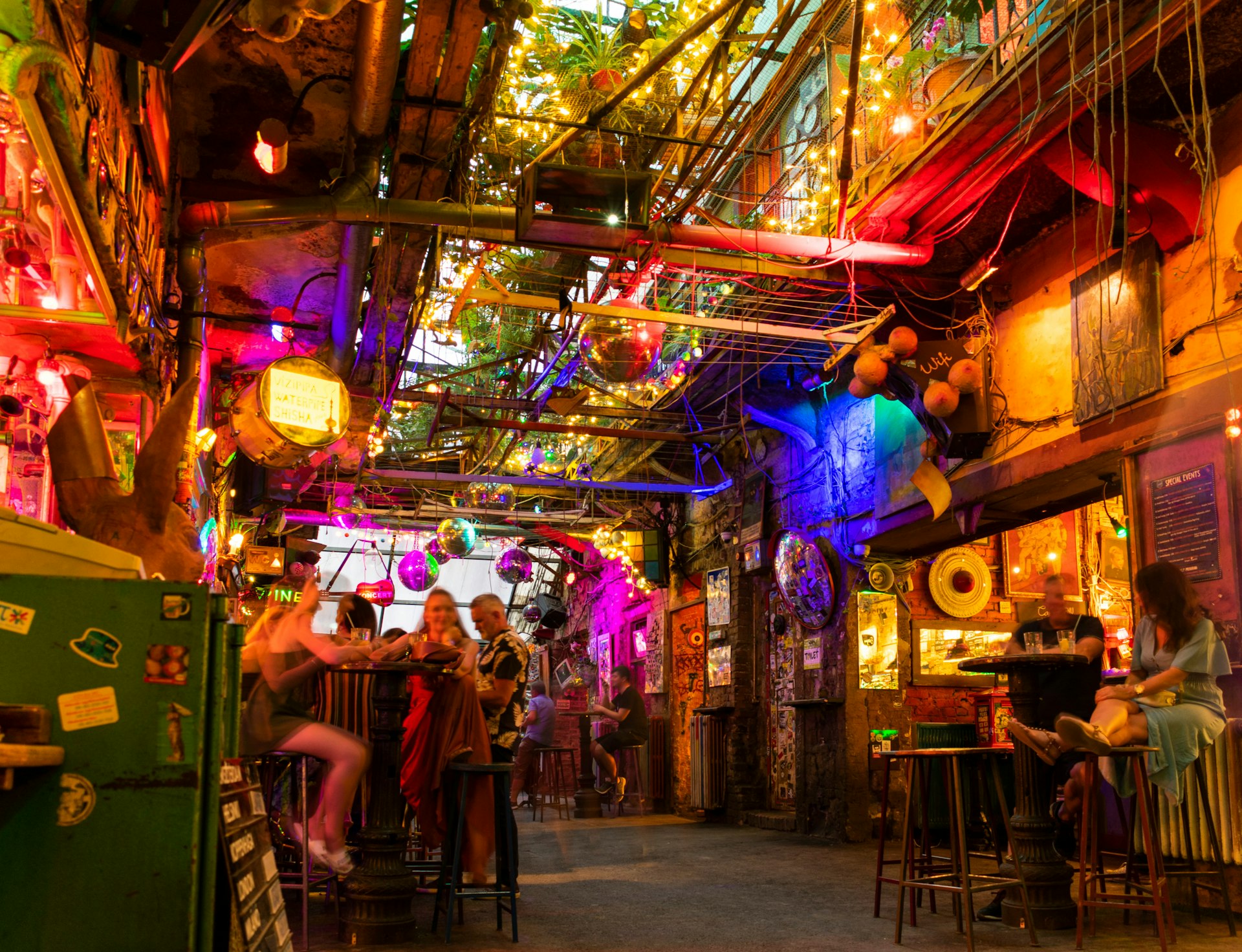 A bar in the evening with people sitting on mismatched furniture