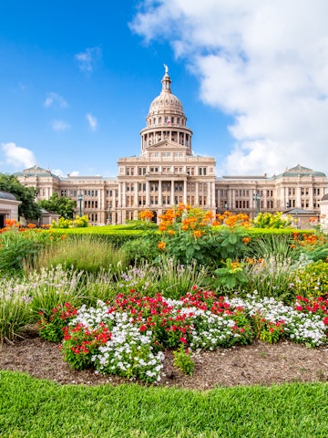 The Texas State Capitol with flower garden. It was completed in 1888 in Downtown Austin. It contains the offices and chambers of the Texas Legislature and the Office of the Governor.