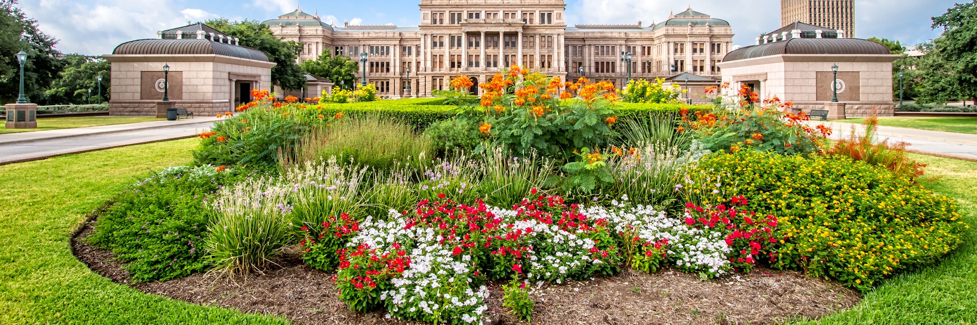 The Texas State Capitol with flower garden. It was completed in 1888 in Downtown Austin. It contains the offices and chambers of the Texas Legislature and the Office of the Governor.