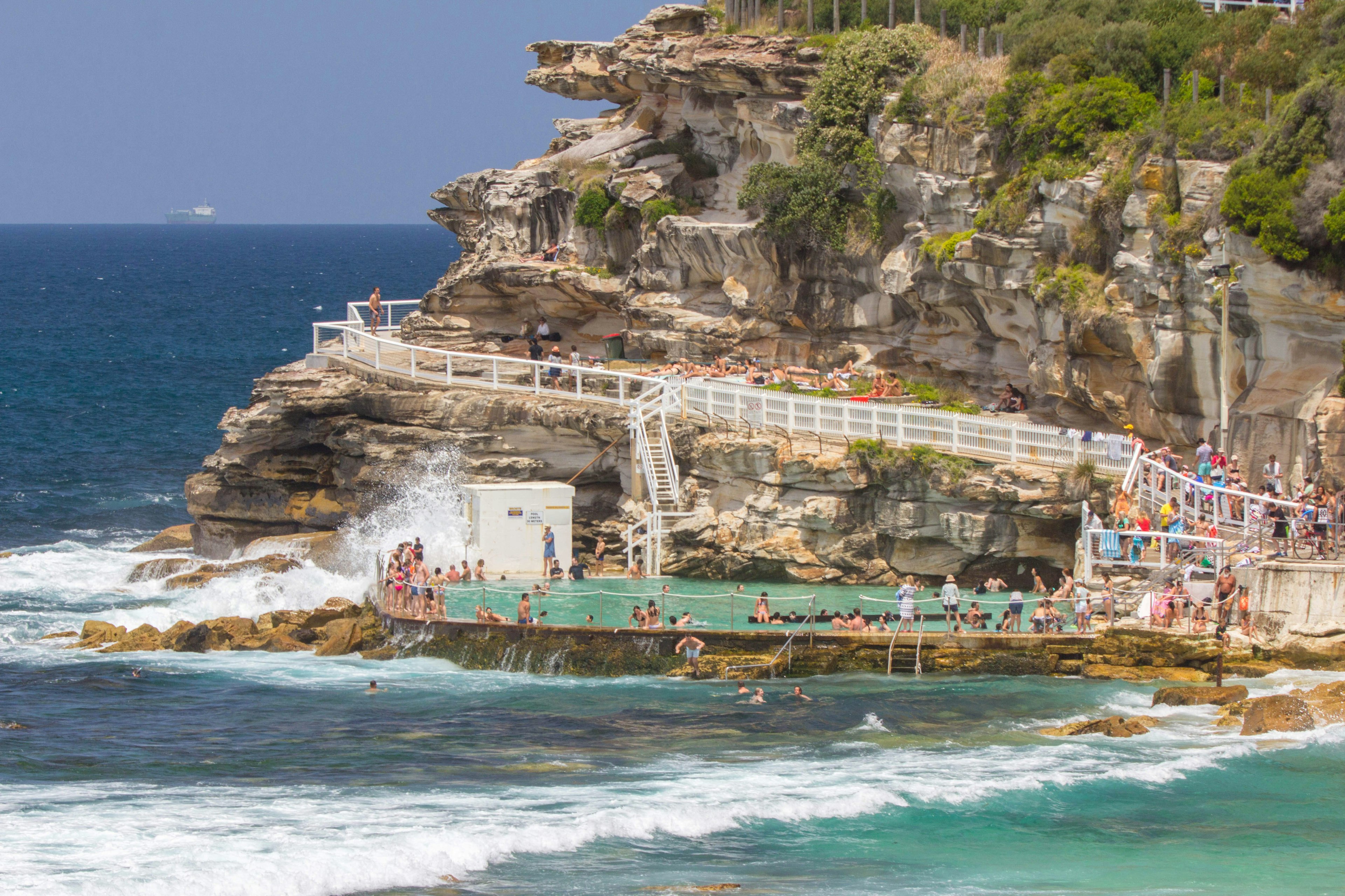 Swimmers in an ocean pool built between the sea and a cliff