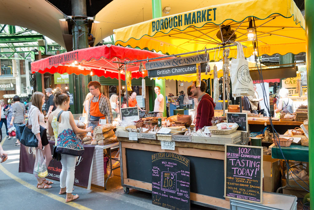 Two market stalls selling bread and charcuterie, with brightly colored awnings over them 