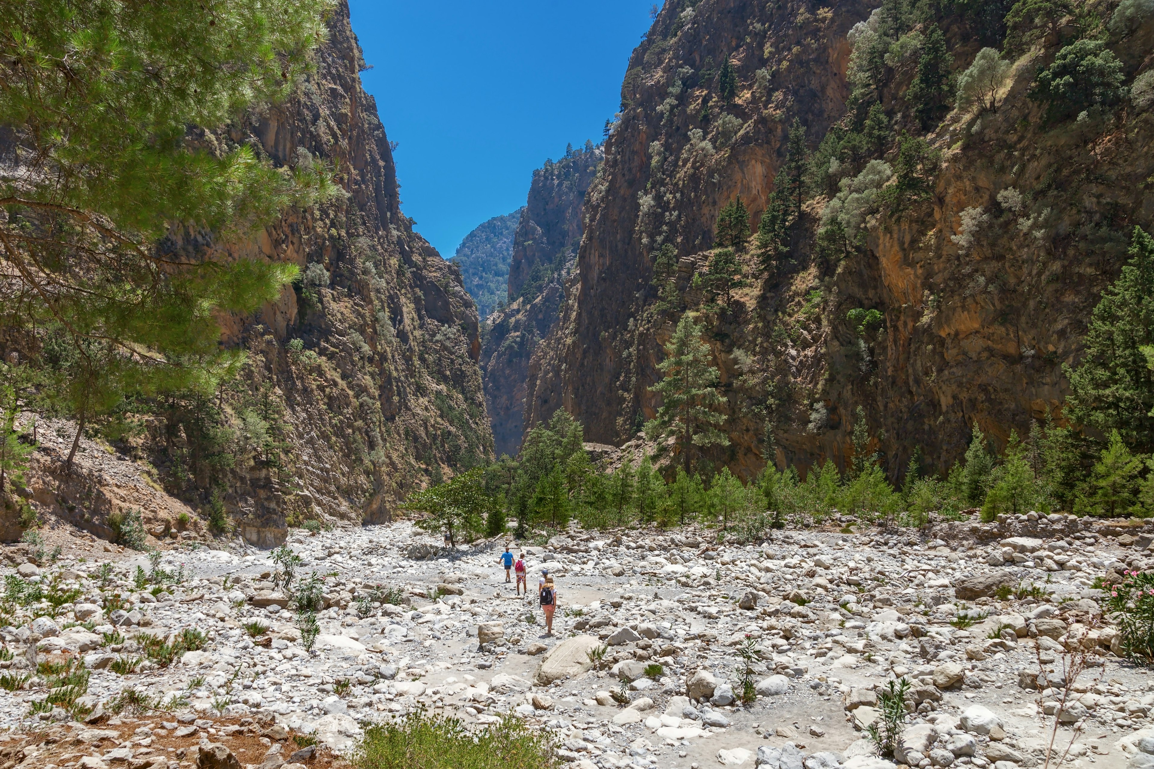 Hikers walking through a dry riverbed at Samaria Gorge in the White Mountains.