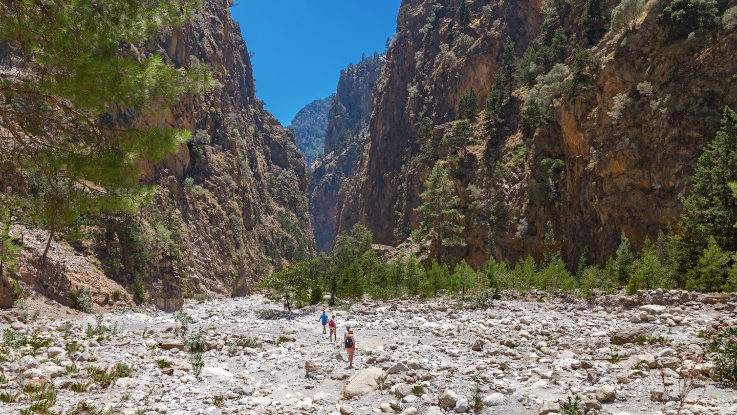 Hikers walking through a dry riverbed at Samaria Gorge in the White Mountains.