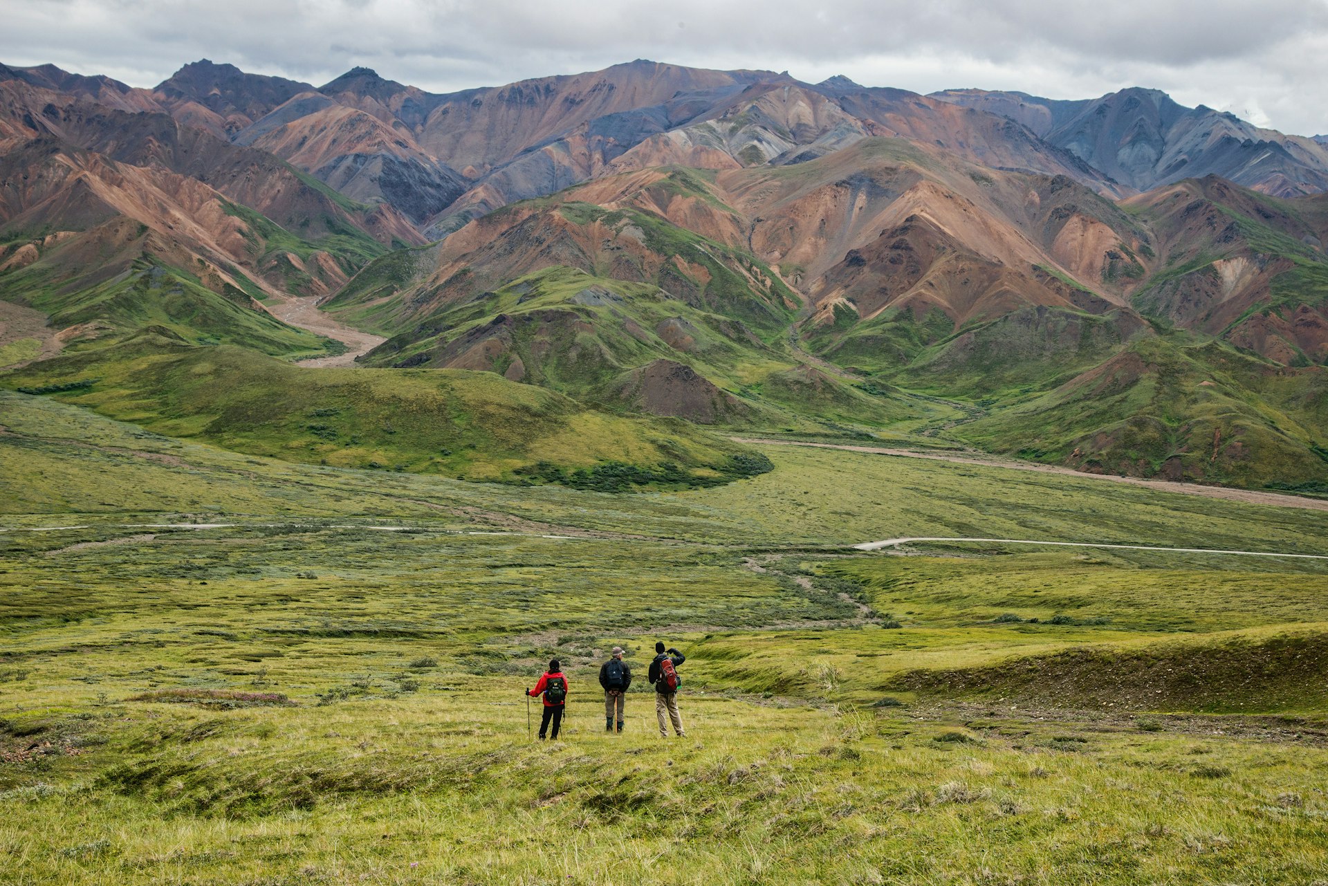 Hikers in a treeless landscape, with mountains in the background
