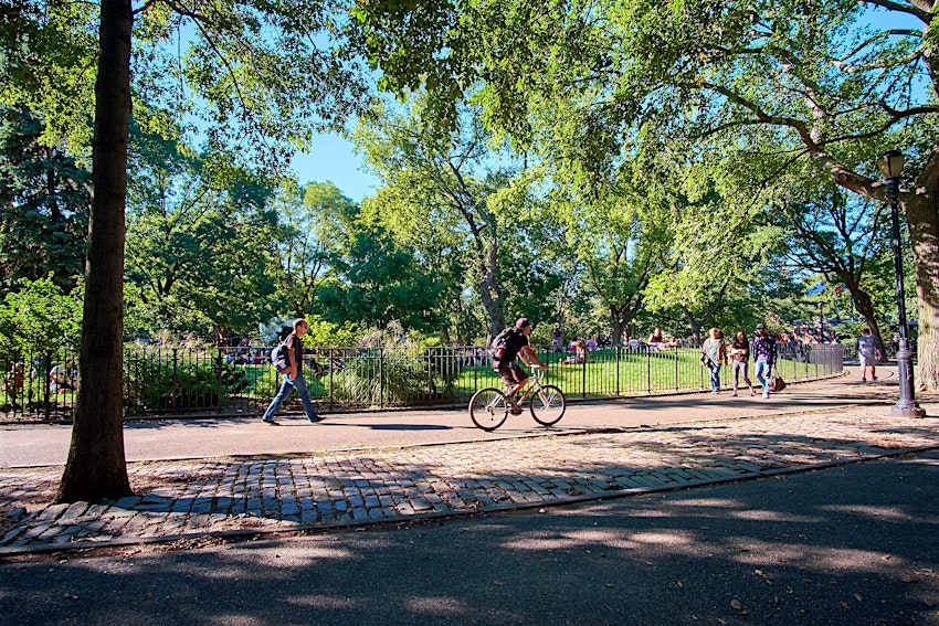 People walking and cycling in Tompkins Square Park in East Village on a warm October day. 