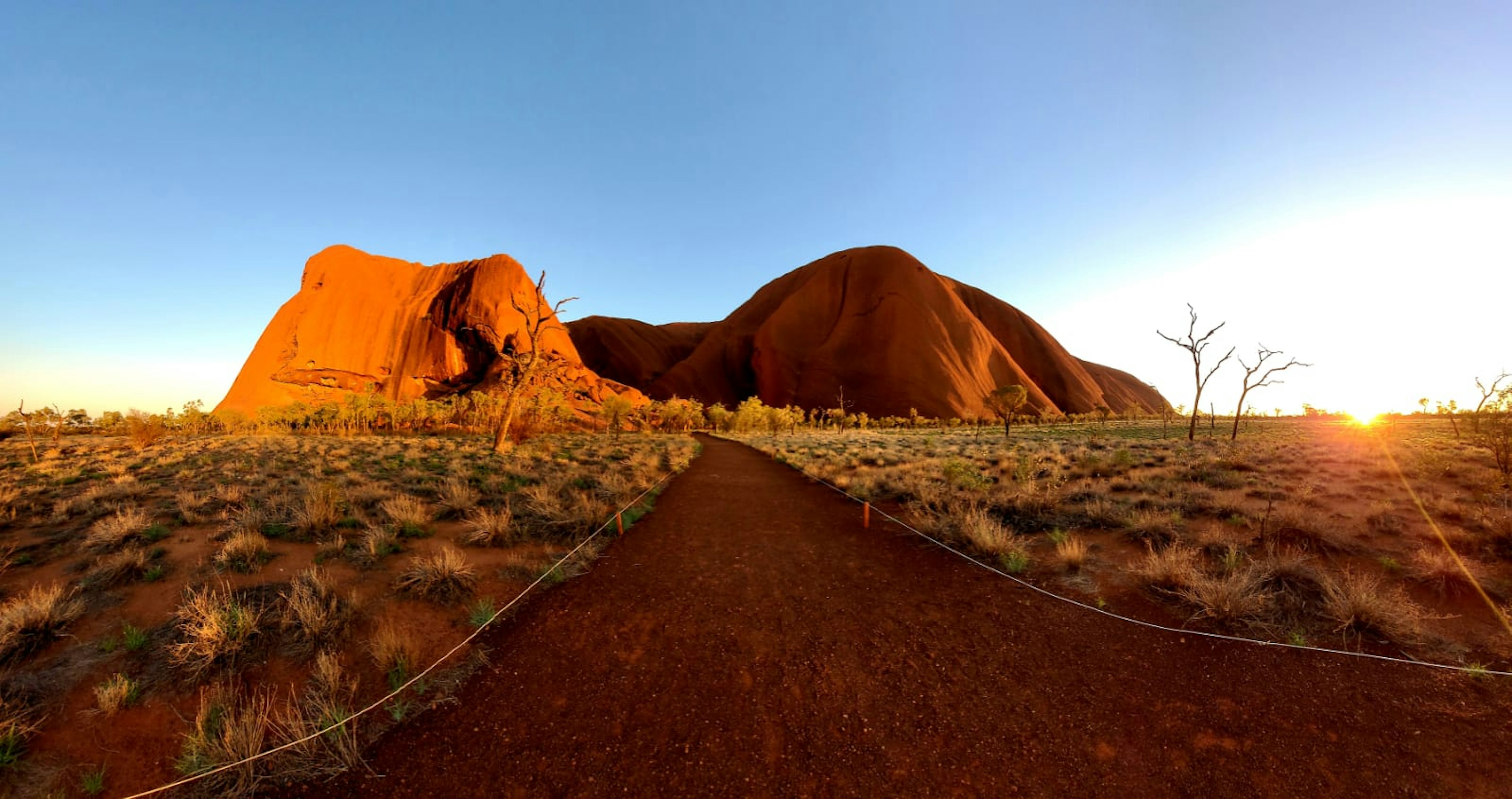 A dirt path leads towards a vast flat-topped mountain