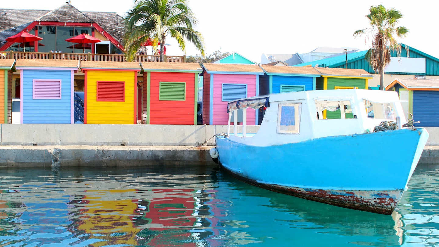 A colorful image of the waterfront area in downtown Nassau showing a water taxi and several huts.