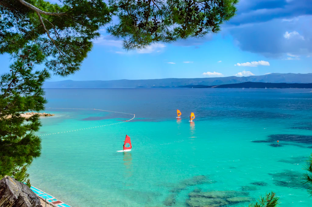 Windsurfers on sailboards in turquoise sea water 