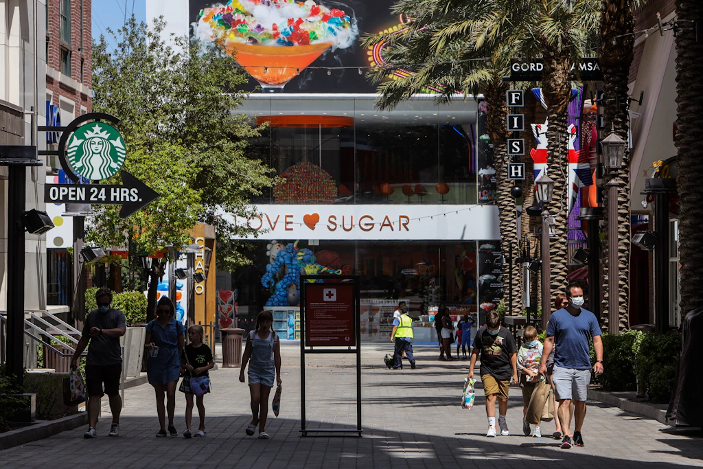 Shoppers wonder along the pedestrianized LINQ Promenade with the I LOVE SUGAR shop in the background.