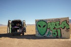 ALAMO, NEVADA - JANUARY 24: 'Vanlifer' Mary Alice Sandberg poses for a photo in a converted Sprinter Campervan next to Area 51 graffiti on January 24, 2021 in Alamo, Nevada. (Photo by Josh Brasted/Getty Images)