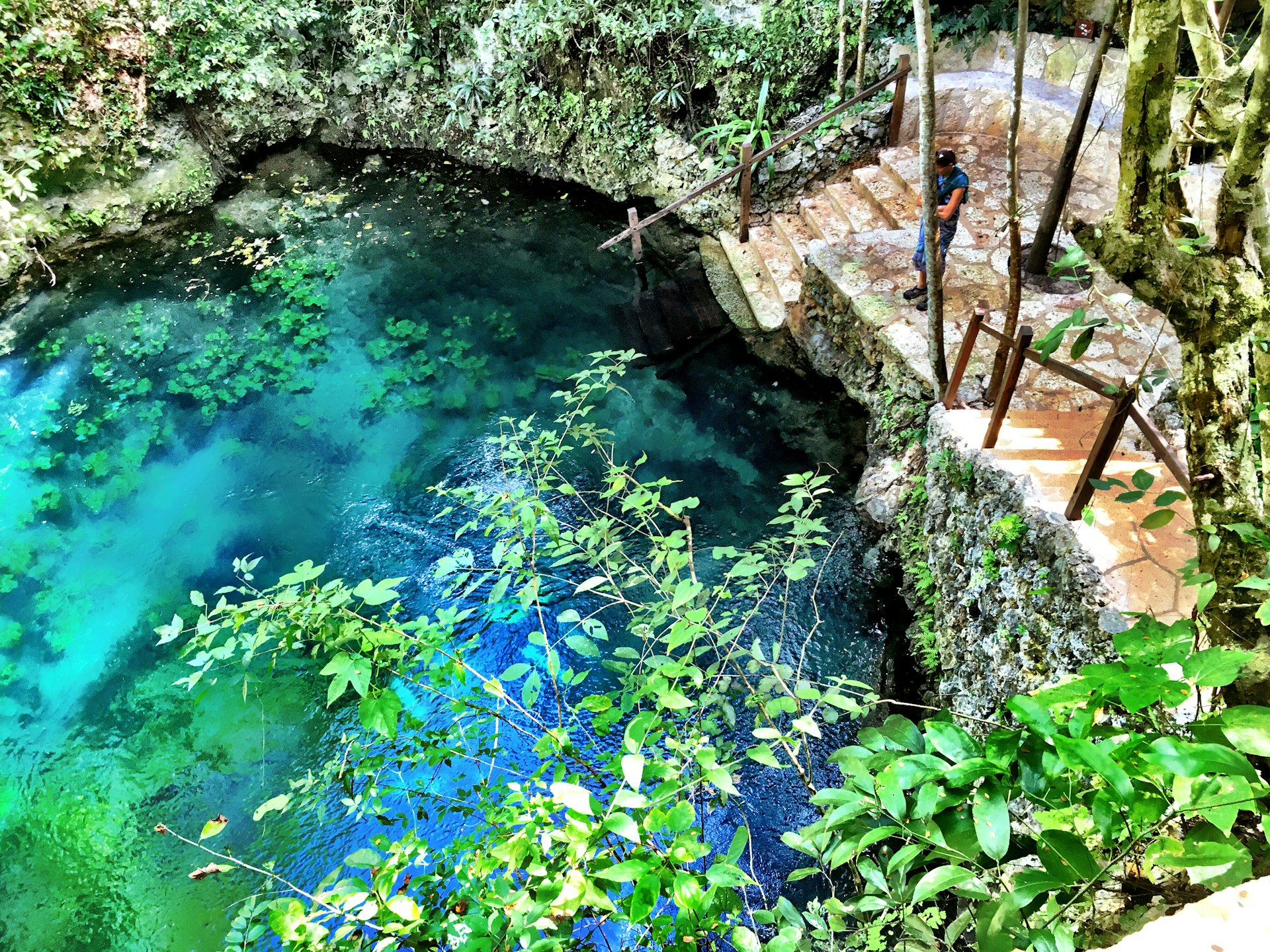Man standing near turquoise blue Cenote Zapote, near Puerto Morelos in Quintana Roo, Mexico