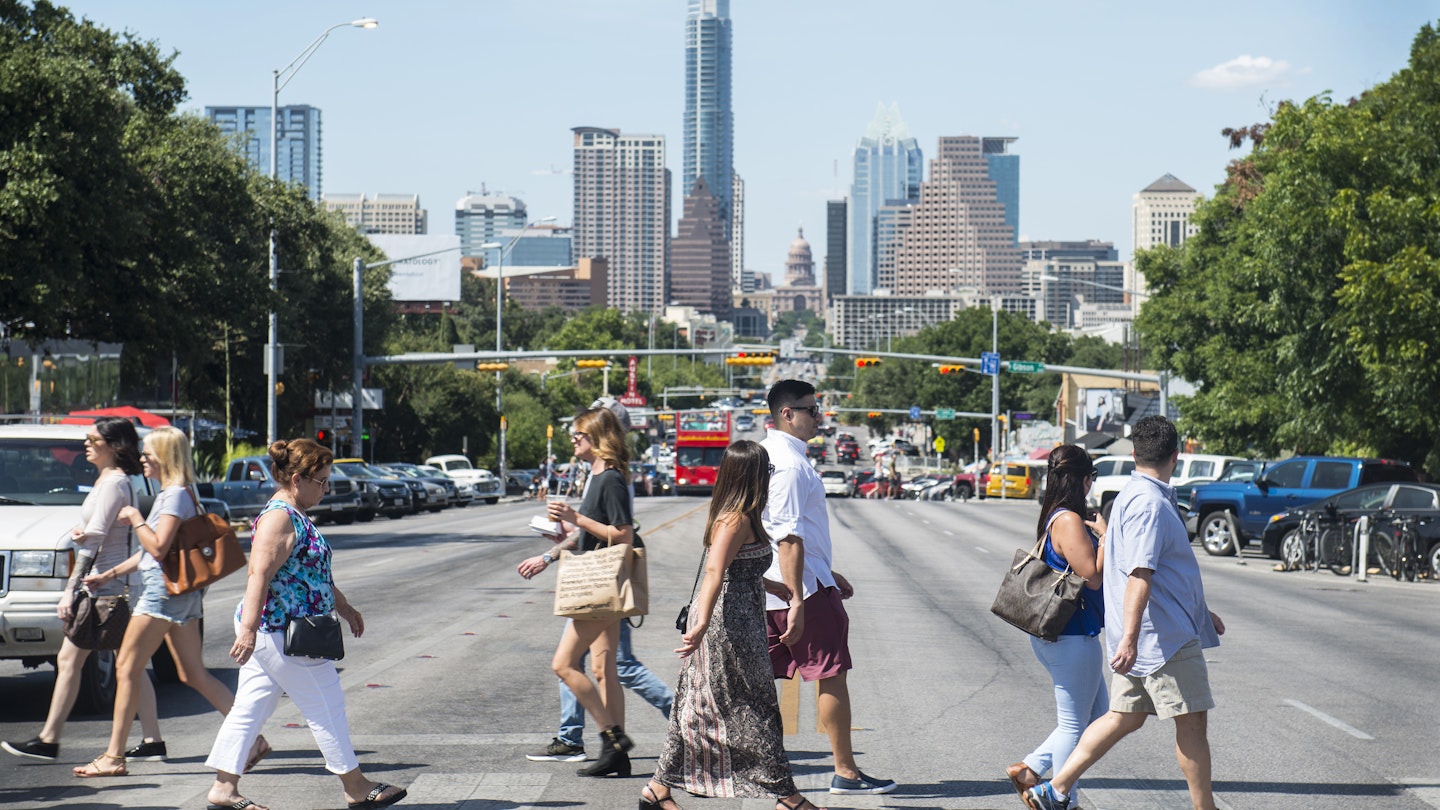 Pedestrians cross South Congress Avenue with the downtown skyline seen in the background in Austin, Texas, U.S., on Saturday, July 23, 2016. Consumer confidence was little changed in July as Americans remained positive about the job market and the business environment, according to a report from the New York-based Conference Board on Tuesday. Photographer: Matthew Busch/Bloomberg via Getty Images