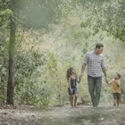 Hispanic father walking son and daughter in woods