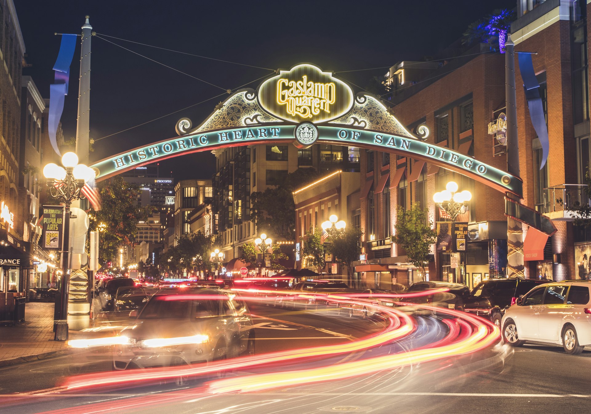 A night time shot of a busy street scene. A large banner sign reads "Gaslamp Quarter: historic heart of San Diego".