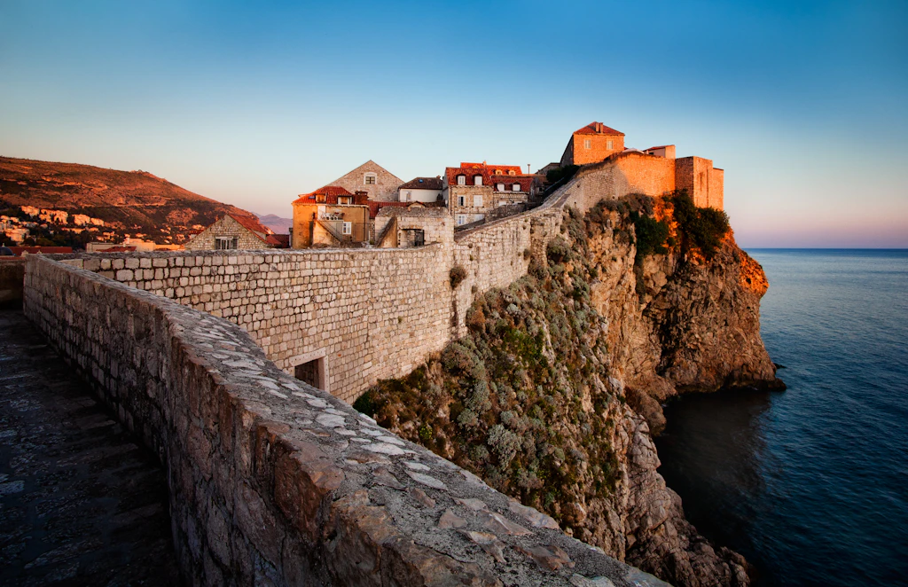 Dubrovnik city walls City walls stretch up a slope towards a fortified tower