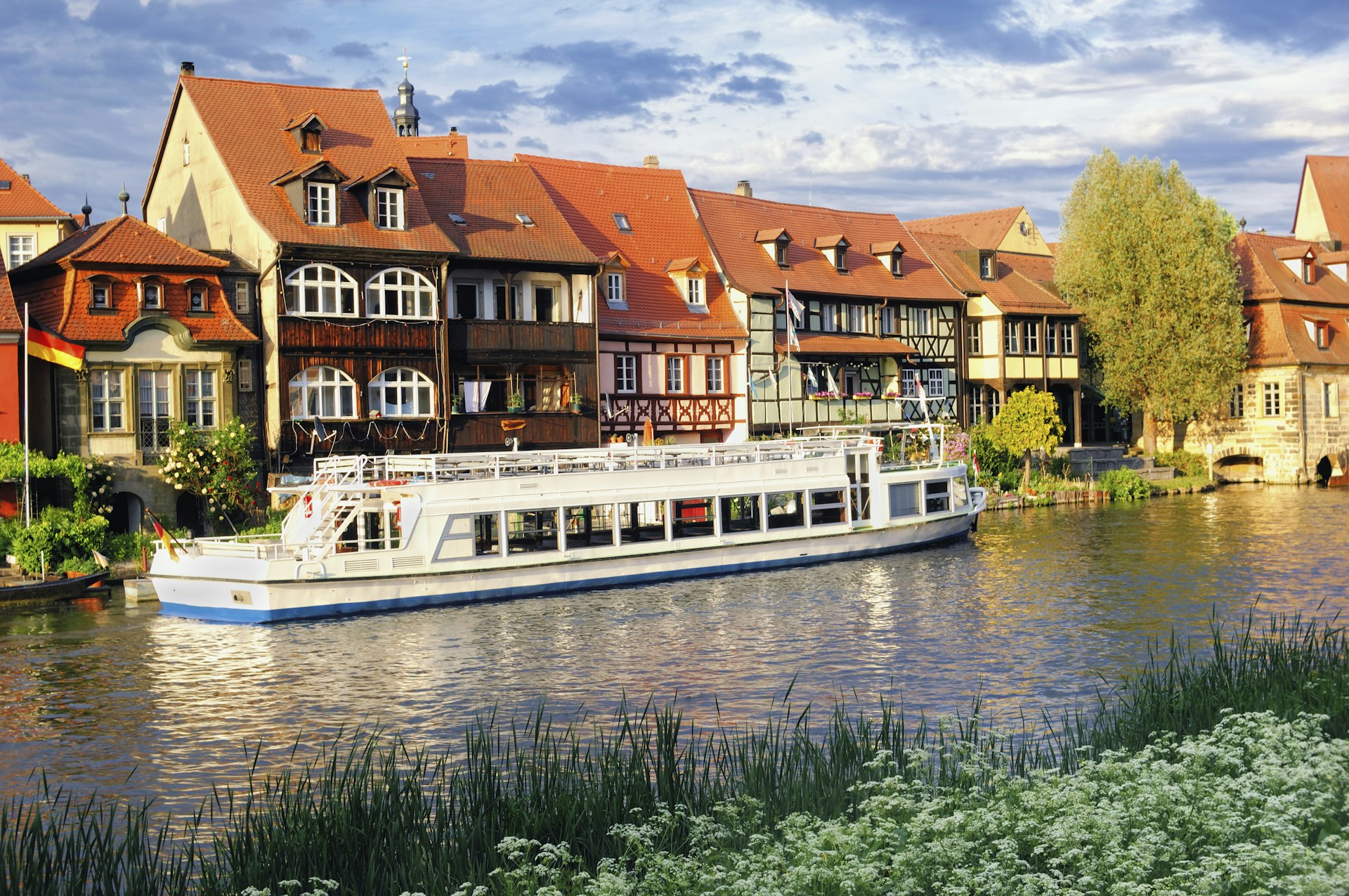 A sightseeing boat docked in front of old fisher houses in a river