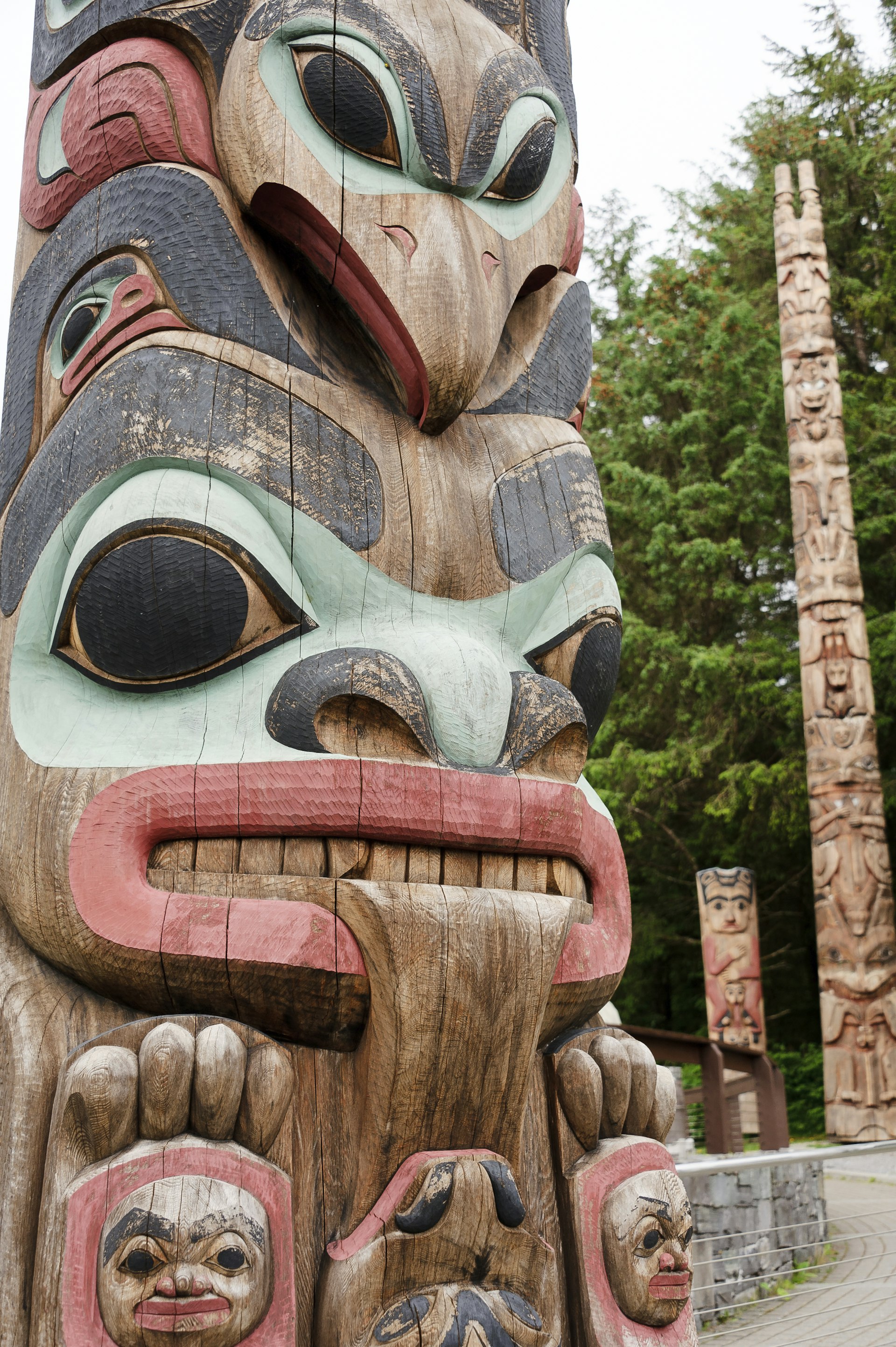 Three totem poles stand among trees