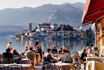 Lake Orta, Italy - February 24, 2012: People enjoy lunch in a lakeside restaurant. With the nearby Unesco site Sacro Monte and San Giulio island, Orta is a popular destination for small-scale tourism.