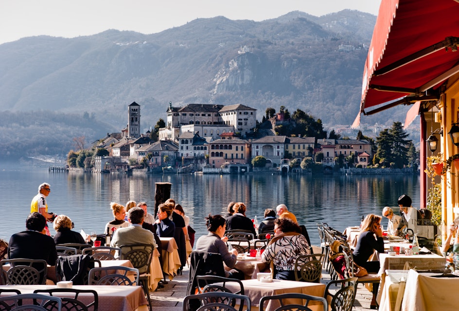 Lake Orta, Italy - February 24, 2012: People enjoy lunch in a lakeside restaurant. With the nearby Unesco site Sacro Monte and San Giulio island, Orta is a popular destination for small-scale tourism.
