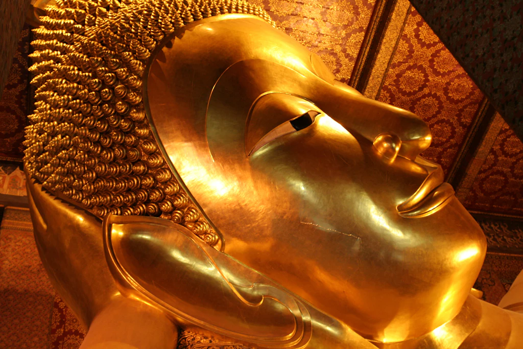 Reclining Buddha The smiling face of the massive Reclining Buddha in Bangkok in gold leaf