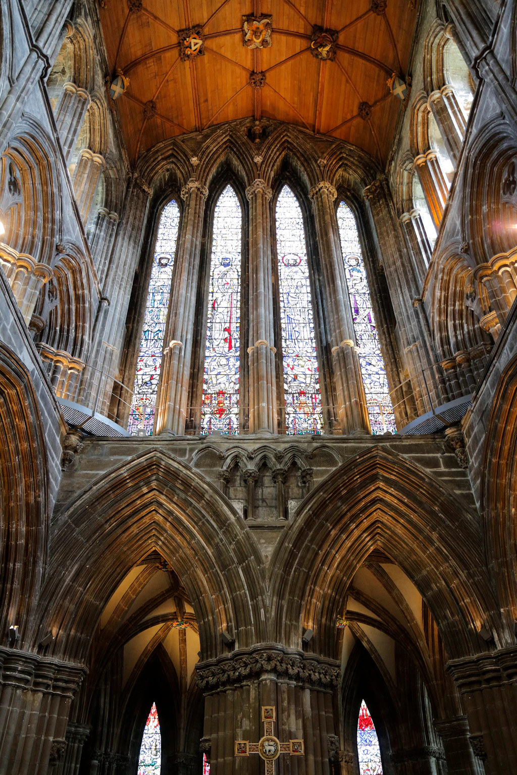 An upwards shot to a huge series of stained glass windows above two arched doorways